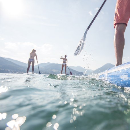 SUP-Paddler auf dem glitzernden Tegernsee mit Blick auf den Wallberg und das bayerische Voralpenland., © Hansi Heckmair