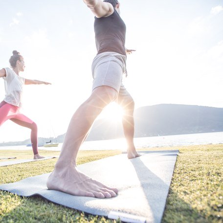 Yogaklasse hat Spaß bei morgendlichen Übungen im Sonnenschein am Ufer des Tegernsees in Bad Wiessee, © Hansi Heckmair