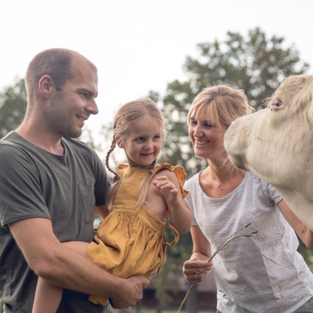 Family stroking cow, © Hansi Heckmair