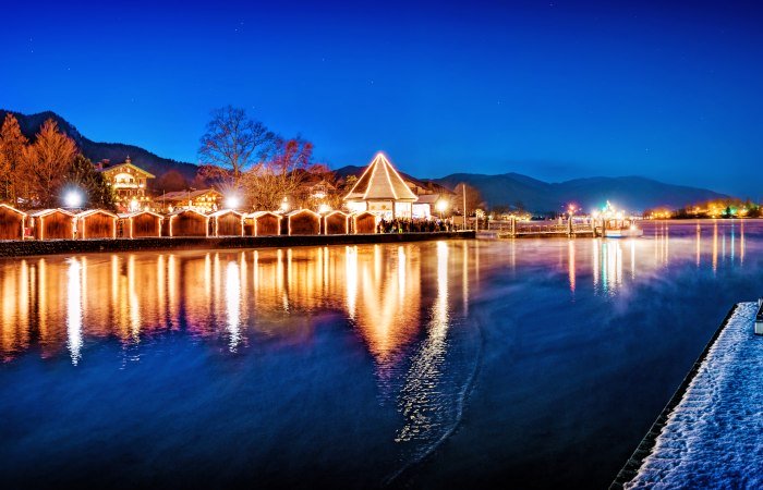 Die glitzernden Lichter der Weihnachtsmärkte spiegeln sich zur Weihnachtszeit im Tegernsee in den Bayrischen Voralpen., © Stefan Schiefer