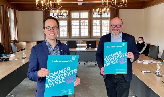 Der Wiesseer Bürgermeister Robert Kühn (l.) präsentiert mit TTT-Geschäftsführer Christian Kausch das neue Plakat #wiesseerocks .  , © Der Tegernsee