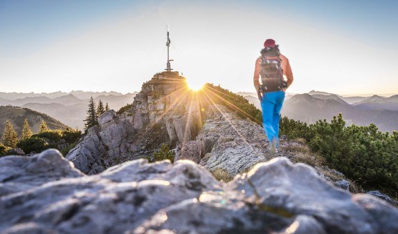 Wanderer bei Sonnenaufgang kurz vor dem Gipfelkreuz Wallberg, © Dietmar Denger