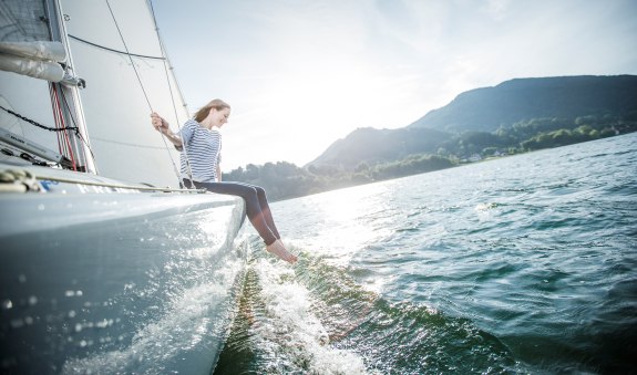 Eine junge Frau genie&szlig;t das erfrischende Nass des Tegernsees beim Segeln., &copy; Hansi Heckmair