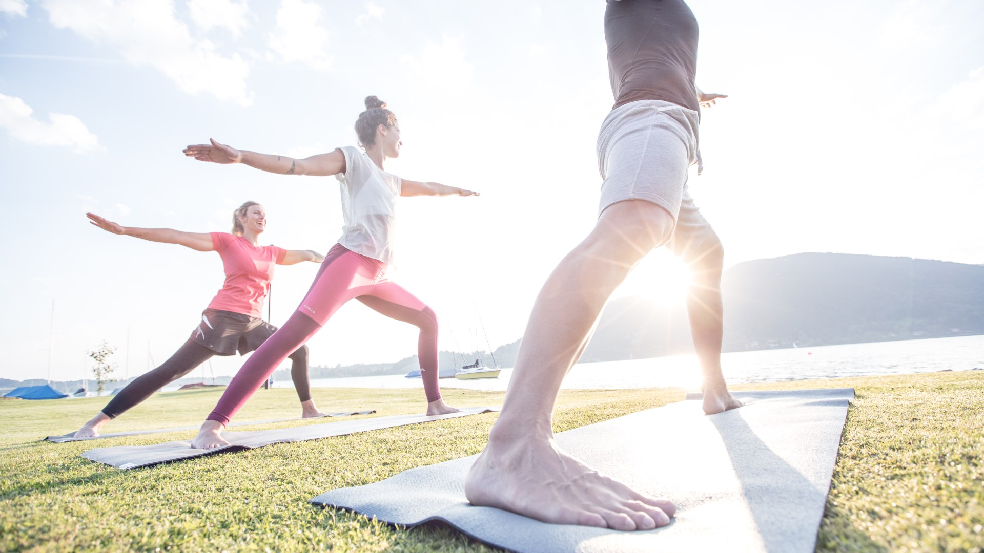 Yogaklasse hat Spaß bei morgendlichen Übungen im Sonnenschein am Ufer des Tegernsees in Bad Wiessee, © Hansi Heckmair